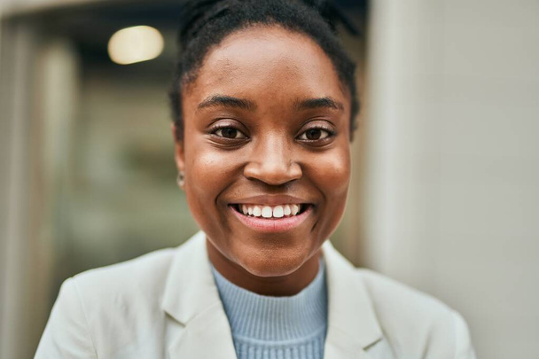 Młoda afrykańska bizneswoman uśmiecha się szczęśliwy stojąc w mieście. - Zdjęcie, obraz