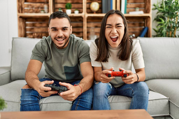 Genç Latin çift evde video oyunu oynarken hayal kırıklığına uğradı. - Fotoğraf, Görsel