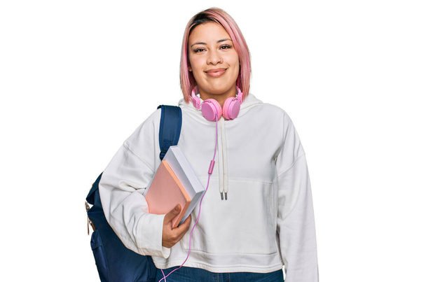 Hispanic woman with pink hair wearing student backpack and headphones with a happy and cool smile on face. lucky person.  - Foto, imagen