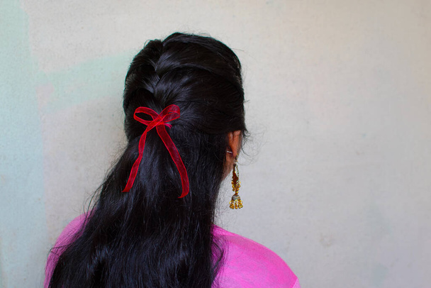 Une Indienne a noué un ruban rouge sur ses cheveux pour soutenir les personnes vivant avec le VIH ou le sida. Le ruban rouge est le symbole universel de la sensibilisation au sida. - Photo, image