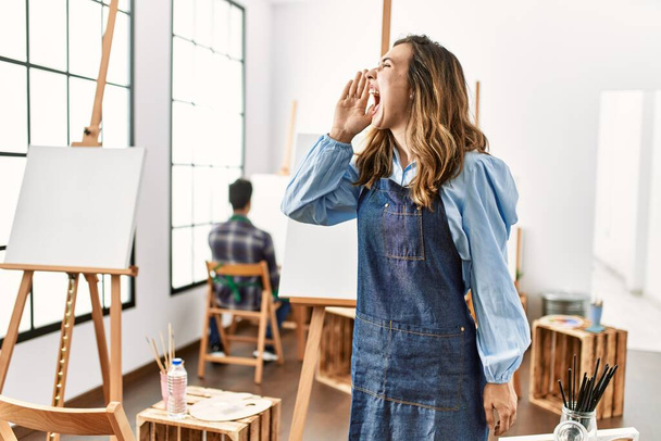 Sanat stüdyosundaki genç sanatçı kadın el pençe divan durup bağırıyor. iletişim konsepti.  - Fotoğraf, Görsel