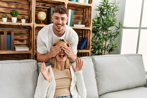Man surprising his girlfriend with hands on eyes at home. - Foto, immagini