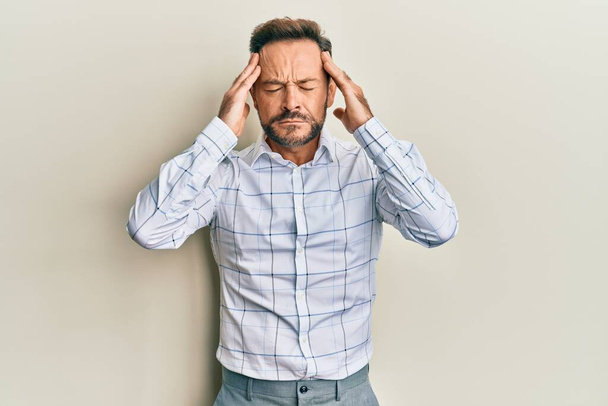 Middle age man wearing business clothes suffering from headache desperate and stressed because pain and migraine. hands on head.  - Foto, afbeelding