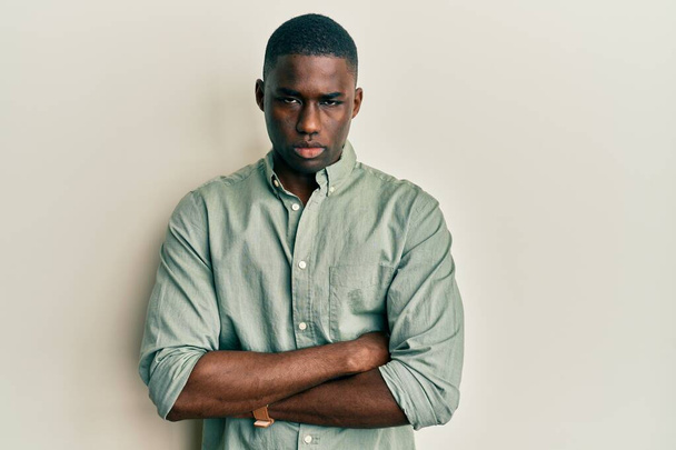 Fiatal afro-amerikai férfi alkalmi ruhát visel szkeptikus és ideges, rosszalló kifejezés az arcon keresztbe tett karokkal. negatív személy.  - Fotó, kép