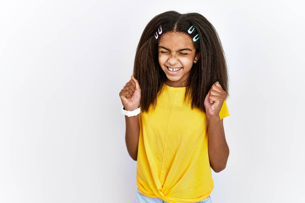 Young african american girl standing over white isolated background excited for success with arms raised and eyes closed celebrating victory smiling. winner concept.  - Fotografie, Obrázek