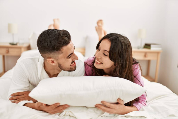 Jeune couple hispanique souriant heureux couché au lit à la maison. - Photo, image