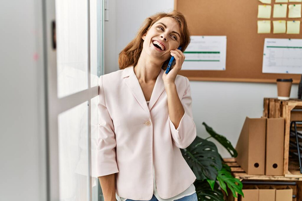 Jovem mulher de negócios caucasiana conversando no smartphone no escritório. - Foto, Imagem
