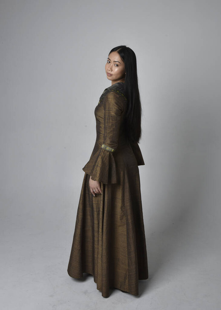 Retrato de larga duración de una hermosa mujer asiática joven con el pelo largo con traje de vestido de fantasía medieval. Elegante de pie posando alejándose, aislado en el fondo del estudio. - Foto, imagen