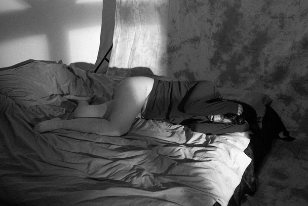 black and white photo of a young woman lying on the bed - Zdjęcie, obraz