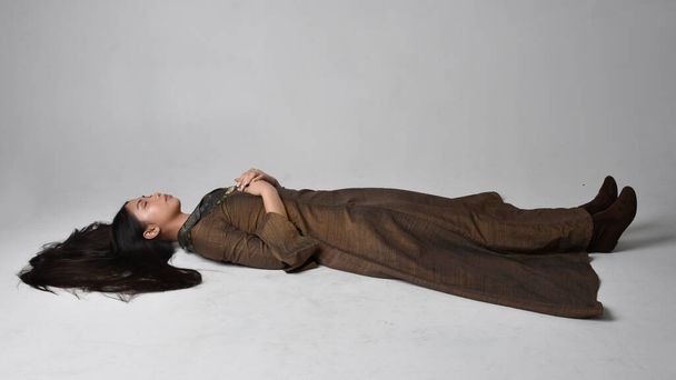 Retrato de larga duración de una hermosa joven asiática con pelo largo y vestido de fantasía medieval. Elegante pose para dormir, aislado en el fondo del estudio. - Foto, imagen