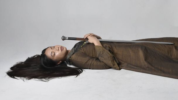 Полный портрет красивой молодой азиатской женщины с длинными волосами в средневековом фэнтези-платье. Изящная спящая поза, изолированная на фоне студии. - Фото, изображение