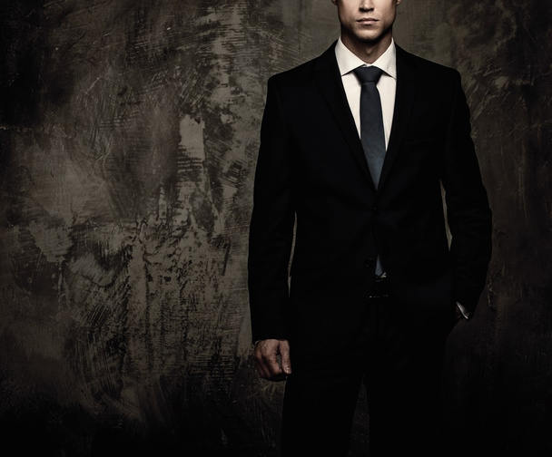 Well-dressed man in black suit against grunge wall  - Photo, Image