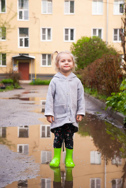 Κοριτσάκι με λαστιχένιες μπότες να περπατάει σε λακκούβες - Φωτογραφία, εικόνα