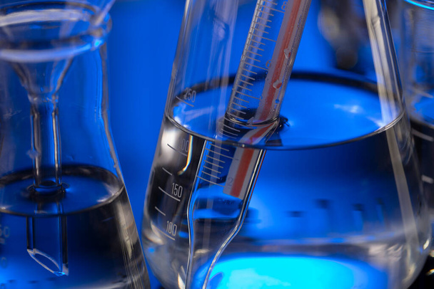 Laboratuvar araştırmaları. Mavi arka planda cam tüpler ve beherler. - Fotoğraf, Görsel