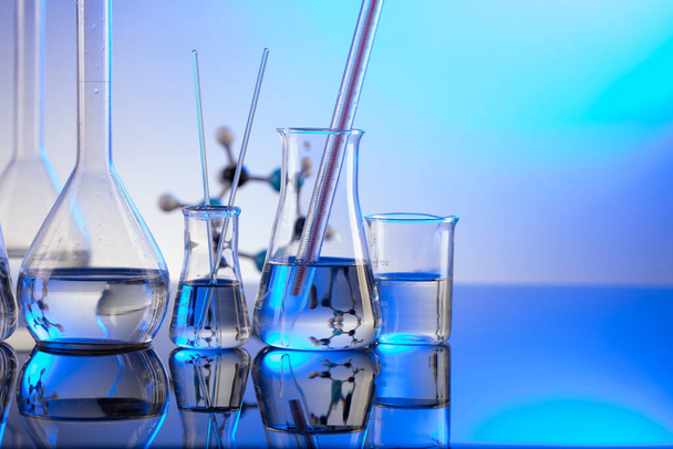 Laboratory investigations. Glass tubes and beakers on blue background. - Φωτογραφία, εικόνα