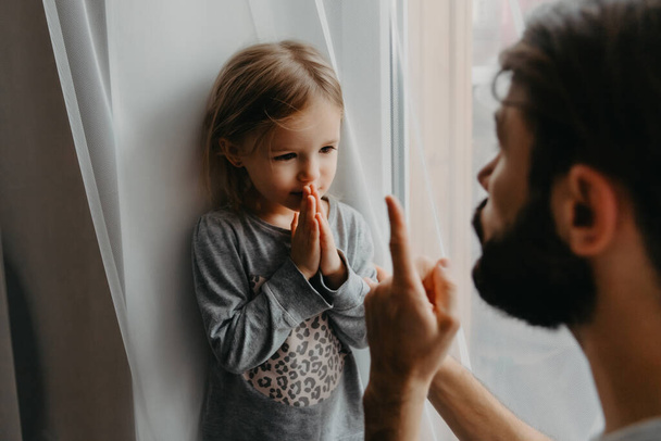 The father puts the child in a corner and makes remarks for bad behavior by waving his index finger near his face. The child does not want punishment and apologizes - Foto, afbeelding