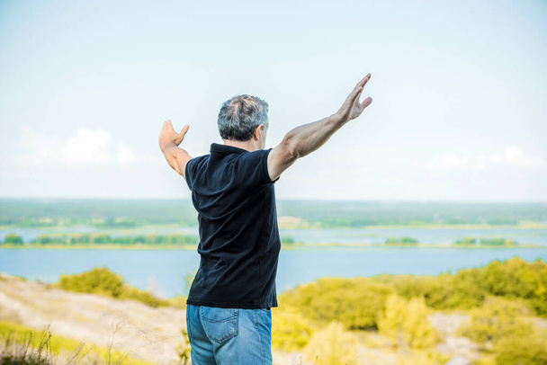 Reifer Mann fühlt Freiheit des Lebens vor dem Hintergrund der Hügel. Senior fällt Bäume  - Foto, Bild