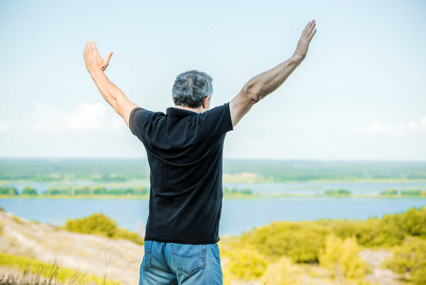 Mature man feels freedom of life against the backdrop of hills. Senior man felling  - Photo, Image
