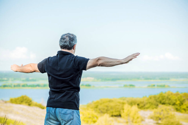 Dospělý člověk pociťuje svobodu života na pozadí kopců. Senior man felling  - Fotografie, Obrázek