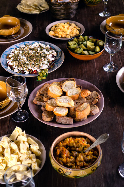 Teller mit köstlichen hausgemachten Gerichten auf einem Holztisch im Freien auf dem Land. Warten auf Gäste zum Feiern oder zum Mittagessen. - Foto, Bild