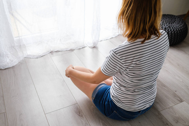 Young woman meditates or practicing yoga in the living room - Foto, Imagem