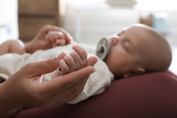Mother with her cute sleeping baby at home, focus on hands - Fotó, kép