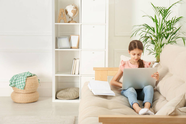 Girl with laptop and book on sofa at home - Photo, image