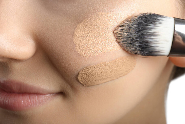 Girl applying foundation and concealer with brush on white background, closeup. Face contouring - Foto, Imagem