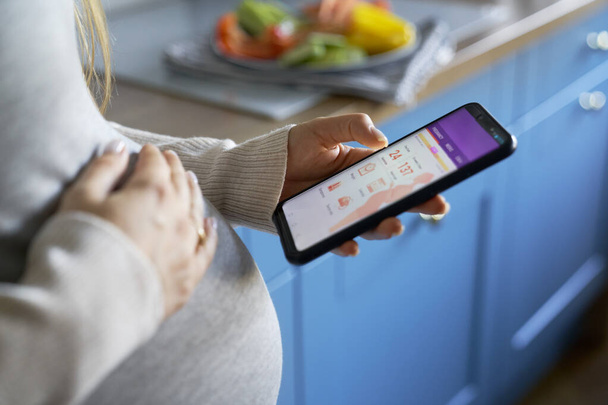 Schwangere nutzt Handy-App auf Smartphone - Foto, Bild