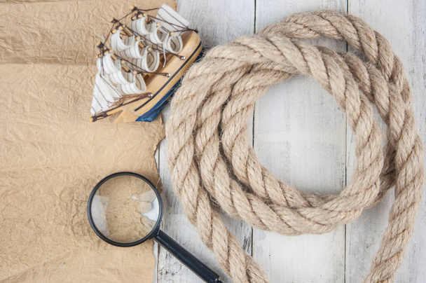 вінтажний чистий папір, конопляна мотузка, збільшуючи скло і модель класичного човна на білому фоні
  - Фото, зображення