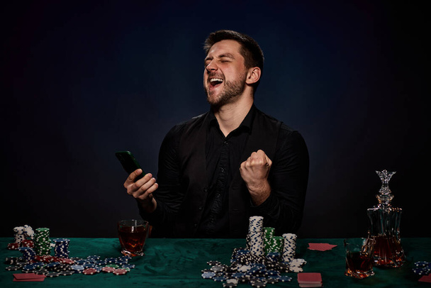 Bearded casino player man playing poker on green table - Фото, изображение