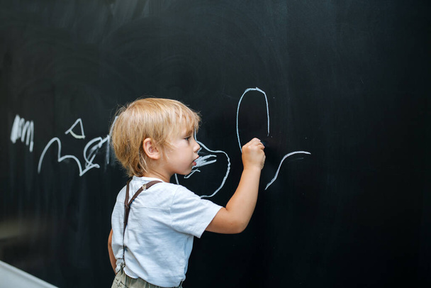 Imaginative playful little boy writing on a board, pretending to be a teacher - Photo, image