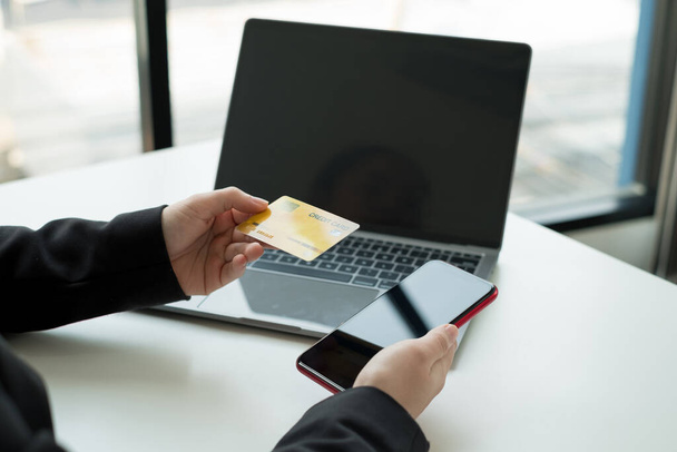 Рука ділової жінки тримає кредитну картку і використовує ноутбук для онлайн-покупки та інтернет-платежів
. - Фото, зображення