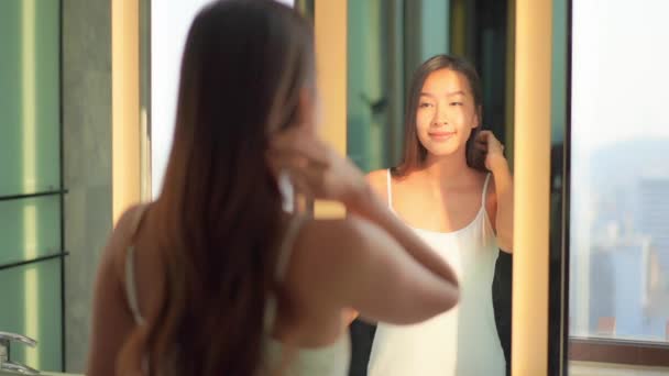 Otelde aynanın önünde makyaj yapan güzel Asyalı bir kadının görüntüsü. - Video, Çekim