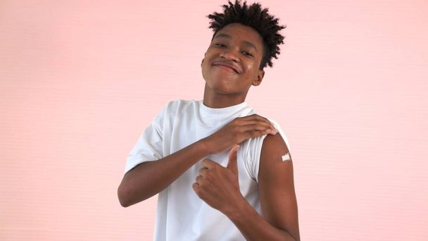 Afroamerikanischer Teenager zeigt fröhlich COVID-19 Impfverband - Foto, Bild