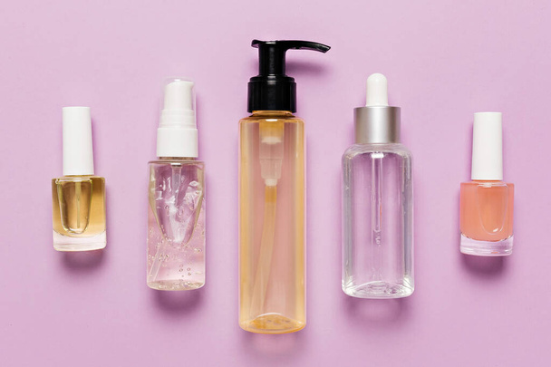 Organic cosmetics packaging design. Flat lay, top view clear glass pump bottle, brush jar, moisturizing serum jar on a purple background. Natural cosmetics SPA - 写真・画像