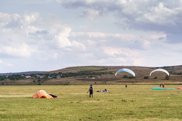 Парапланеристы летят под голубым небом в зеленом поле - Фото, изображение