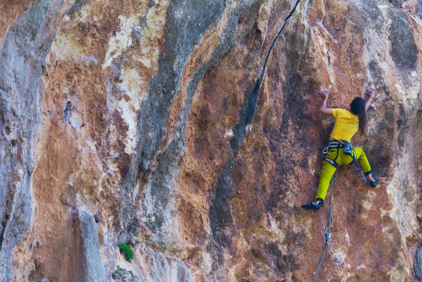 Ein Mädchen erklettert einen Felsen vor dem Hintergrund des Waldes, Der Sportler trainiert in der Natur, Frau überwindet schwierige Kletterroute, Starker Bergsteiger, Extremes Hobby, Klettern in der Türkei. - Foto, Bild