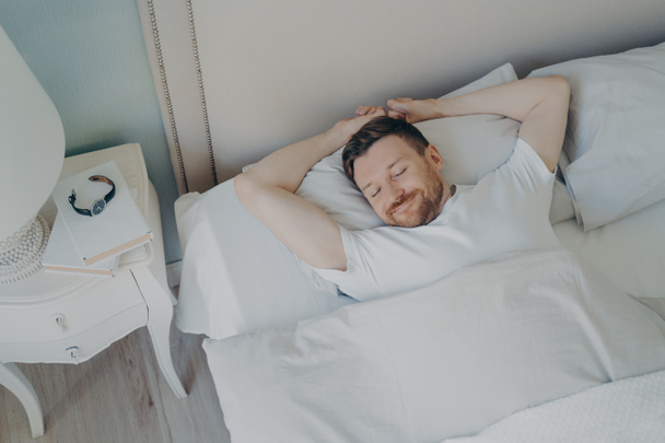 jong gelukkig ontspannen Kaukasische man slapen in bed - Foto, afbeelding