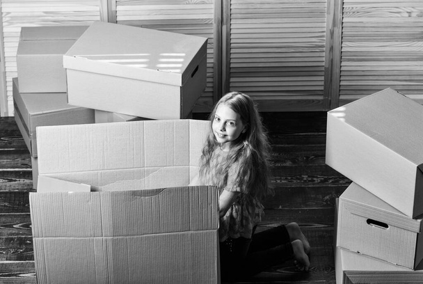 happy child box. repair of room. new apartment. unpacking moving boxes. happy little girl sit in room on boxes. Cardboard boxes - moving to a new house. purchase of new habitation - 写真・画像