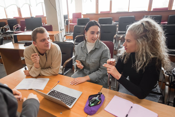 Two girls and a guy are talking in sign language. Three deaf students chatting in a university classroom. - Foto, afbeelding