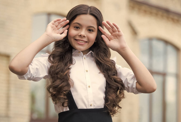 Dare to be beautiful. Happy child fix long curly hairstyle outdoors. Back to school look. School fashion. Beauty look. Hair salon. Elementary education. Knowledge day. September 1 - Photo, Image