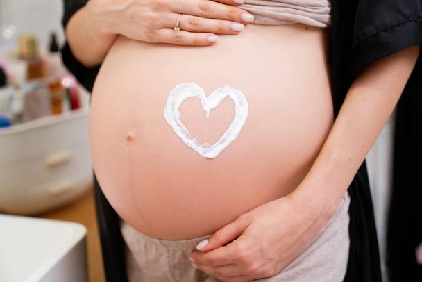 Крупним планом вагітна жінка з формою серця на животі
  - Фото, зображення