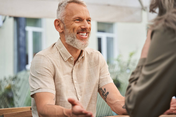 Man smiling toothy while chatting with his wife during the romantic date - Photo, image
