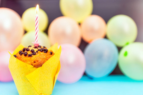 Syntymäpäivä cupcake.Pastel keltainen syntymäpäivä cupcake kynttilä ja hämärtynyt ilmapallot.värikäs syntymäpäivä cupcake värillinen candle.Closeup, kopioi space.Birthday käsite. - Valokuva, kuva
