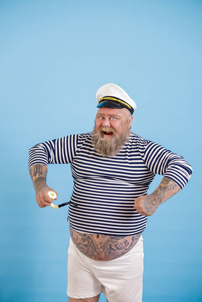 ダッシュプラスサイズ人身に着けている水夫の衣装でパイプポーズ上のライトブルーの背景 - 写真・画像