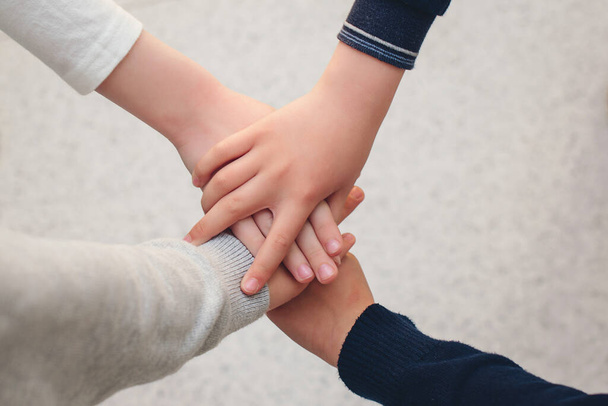 Top view group of children stacking hands outdoors. Concept of friendship, unity and teamwork. Group of school friends with hands stacked one on top of another. Back to school. - Fotografie, Obrázek