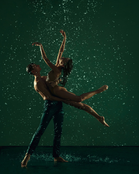Dos jóvenes bailarines de ballet, hombre y mujer bailando en las gotas de lluvia sobre fondo oscuro. Arte, acción, concepto de inspiración. - Foto, imagen