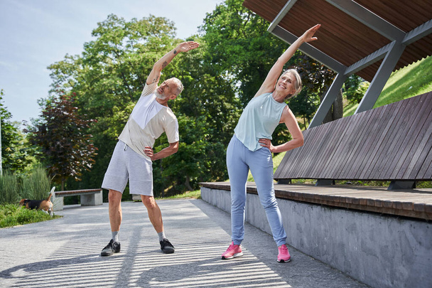 Senior couple training together at the summer park and feeling healthy - Photo, Image