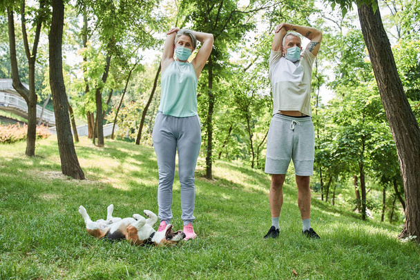 Spouses wearing protective masks feeling healthy while having morning exercises - Фото, изображение